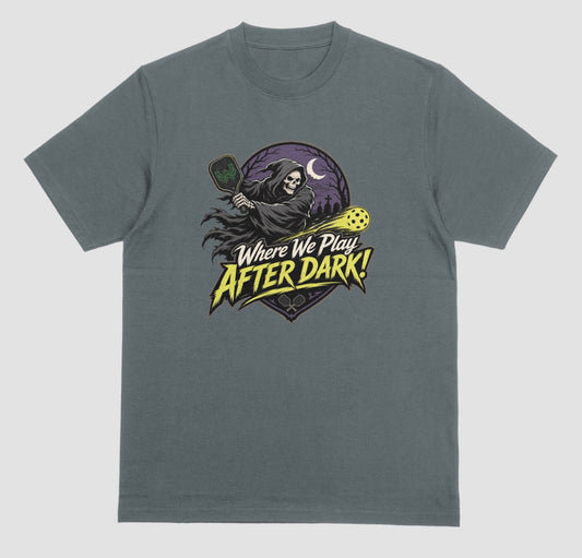 Dark heather gray t-shirt with a spooky pickleball graphic reading 'Where We Play After Dark!' showing a hooded grim reaper swinging a paddle at a glowing yellow ball.
