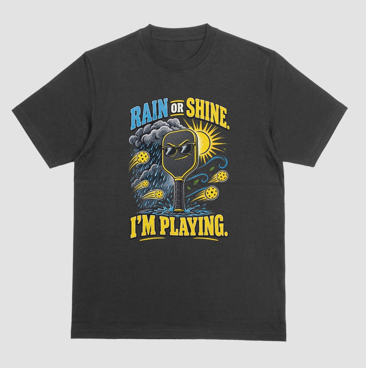 A black Funny pickleball shirt with a sunglasses paddle, storm cloud and sun that says Rain or Shine, I’m Playing