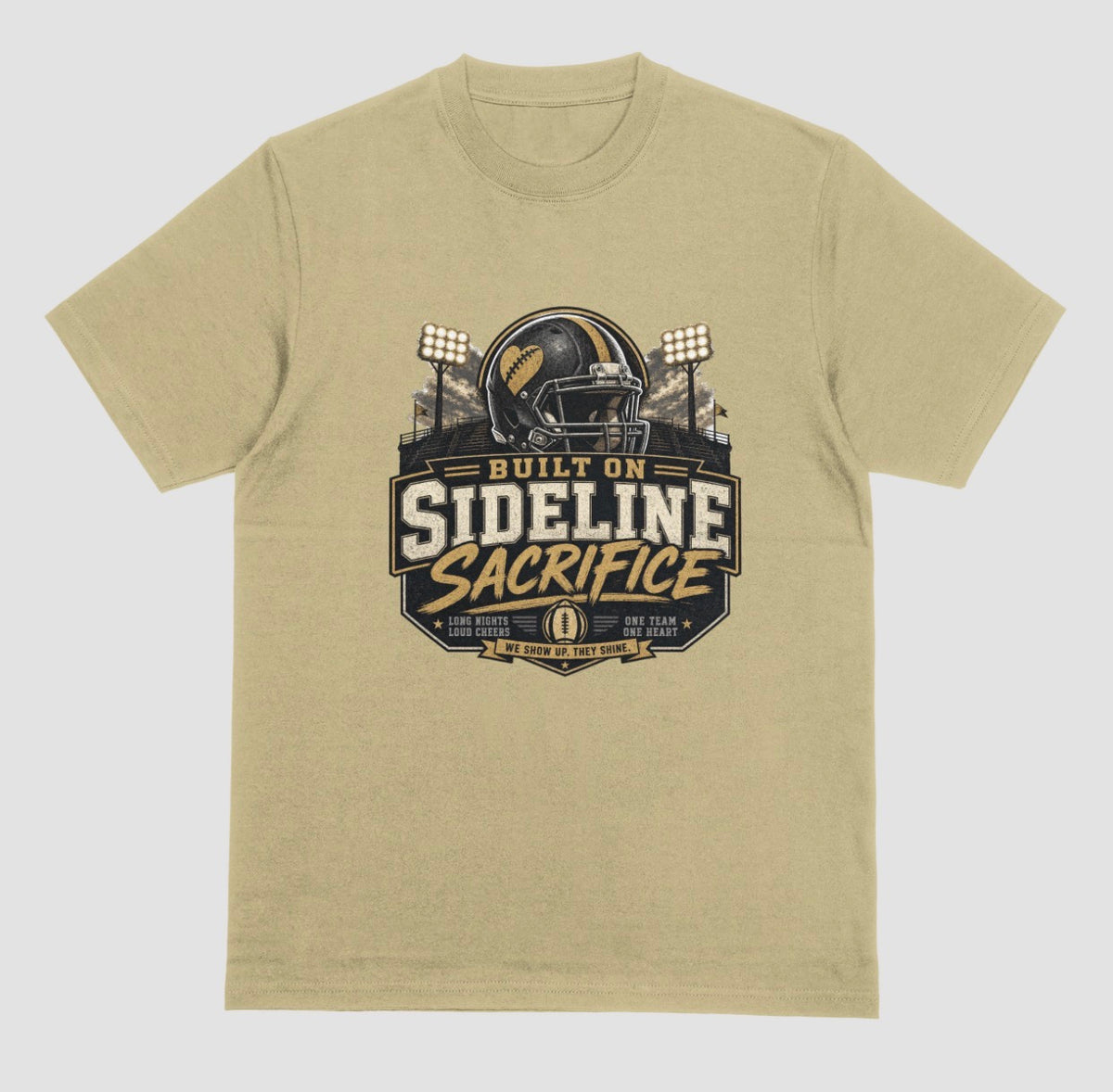 A sand color crewneck t-shirt featuring a football-themed graphic on the chest with the text 'BUILT ON SIDELINE SACRIFICE' and a helmet illustration, shown against a light gray background.