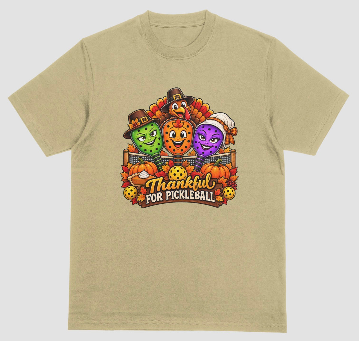 A sand t-shirt with “Thankful for Pickleball” design of three pilgrim-hat paddles, a turkey, pumpkins, and pie