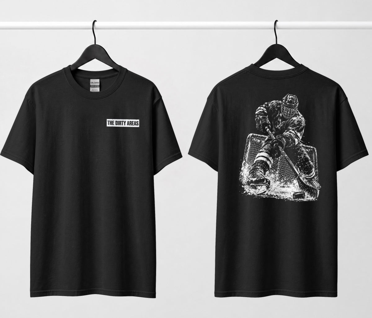 Front and back of a black t-shirt hanging side by side: the front has a small 'The Dirty Areas' label on the chest, and the back has a large white hockey player battling in front of the net.