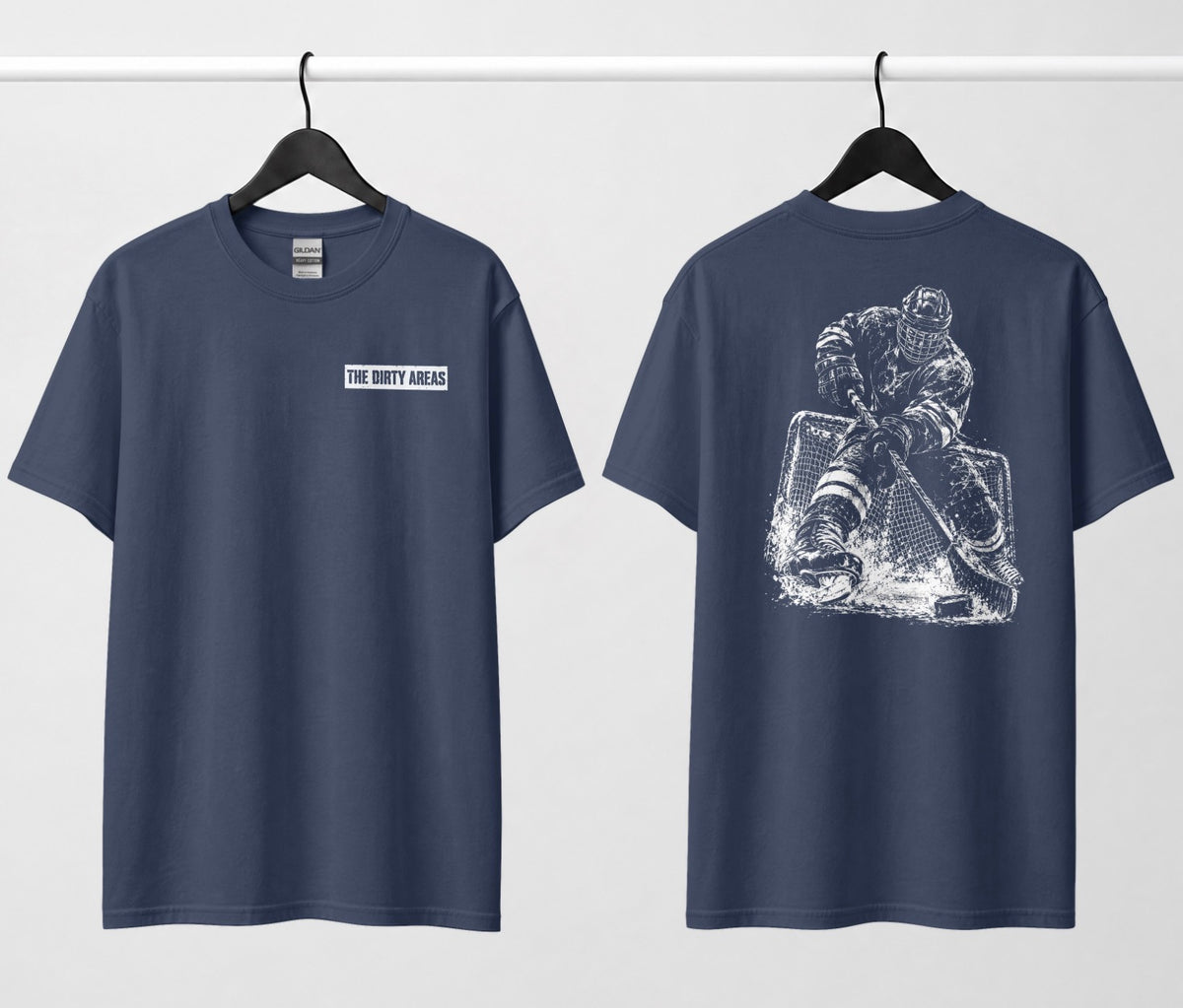 Front and back of a navy blue t-shirt hanging side by side: the front has a small 'The Dirty Areas' label on the chest, and the back has a large white hockey player battling in front of the net.