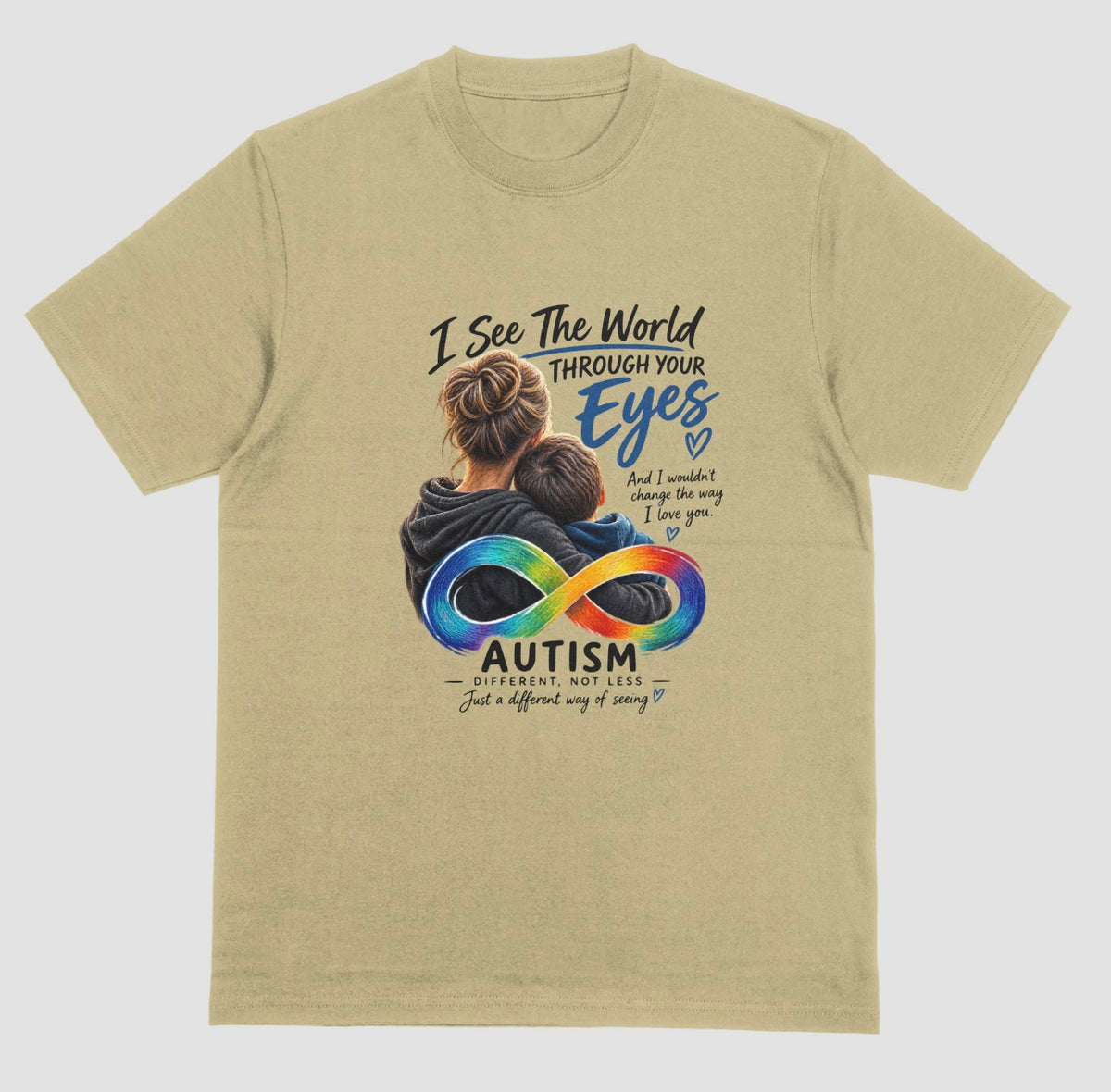 A sand color t-shirt with a graphic of a parent hugging a child, a rainbow infinity symbol, and the text ‘I See the World Through Your Eyes’ and ‘Autism: Different, Not Less.’